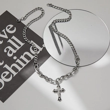 Detail of silver titanium steel snake chain with a textured cross pendant on white