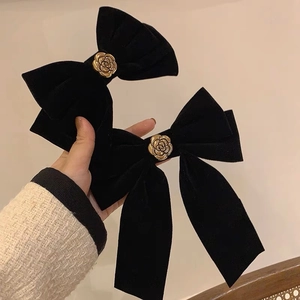 Detail of vintage black velvet bow hair clips featuring a 3D gold metal rose decoration