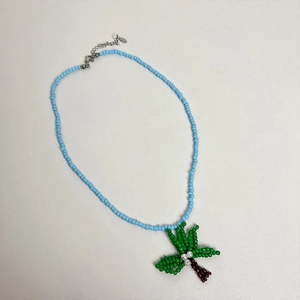 Dettaglio della collana di perline con catena blu e ciondolo a forma di palma verde