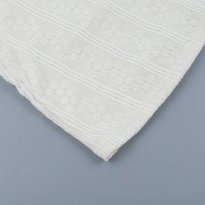 Detailed macro shot of white floral lace fabric with intricate striped patterns