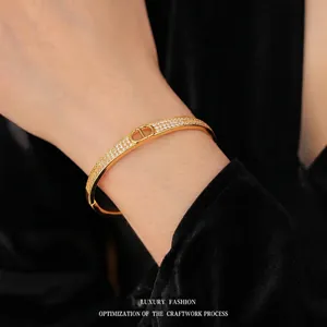 Gold plated fan-shaped bangle with sparkling D-letter logo and pavé-set zircons