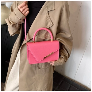 Detail of vibrant pink textured leather handbag featuring elegant gold metal hardware trim