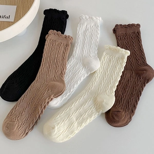 Flat lay of five knitted cotton socks with twist texture and lace cuffs in neutral tones
