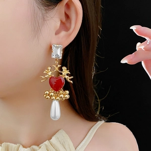 Detail of vintage angel earrings with red heart, golden beads and pearl drop pendant