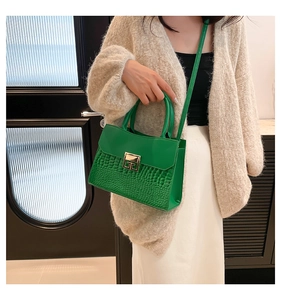 Detail of green PU leather crossbody bag with crocodile pattern and gold square lock