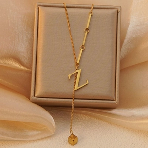 Detail van een gouden ketting met Z-hanger gedrapeerd over een zijden juwelendoos