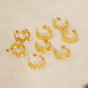 Collection of gold geometric earrings including flower and wave designs on beige background