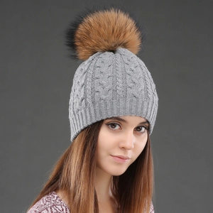 Gray cable knit wool beanie for women featuring a large fluffy faux fur pom-pom