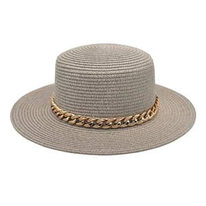 Détail d'un chapeau de paille gris clair avec couronne plate et chaîne en acrylique doré