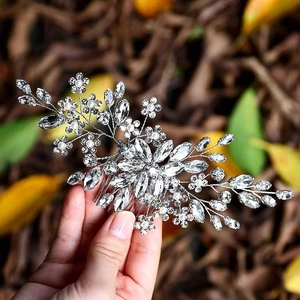 Close-up of bridal hair comb with silver flower motifs, crystals and white pearls