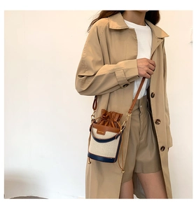 Woman in khaki coat wearing a color-block canvas bucket bag with brown leather trim