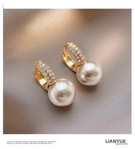 Detail of elegant gold-plated pearl earrings with sparkling pavé zircon accents