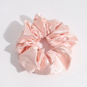 Detailed view of the smooth texture and soft folds of the pink satin silk scrunchie