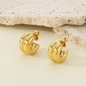 Classic French gold C-shaped stainless steel stud earrings on beige stone base
