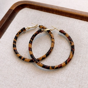 Detailed view of vintage leopard print hoop earrings with golden studs on beige fabric