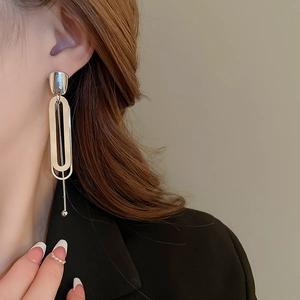 Close-up of a silver double-layered geometric chain earring worn by a model