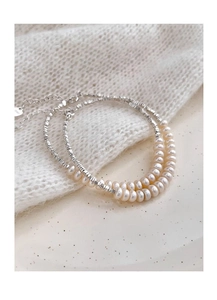 Macro view of freshwater pearls and faceted silver beads on an elegant dainty bracelet