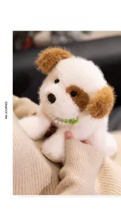 Close-up of a plush white puppy toy with brown spots and a green knitted scarf