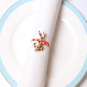 Macro detail of a golden rabbit eating a carrot napkin ring on a white ceramic plate