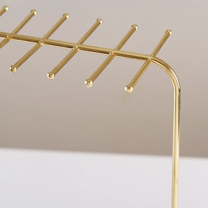 Golden metal necklace display stand with multiple hooks for jewelry storage and organization