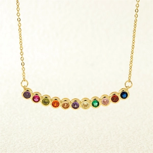 Detail of gold necklace featuring twelve vibrant round colored gemstones in arc design