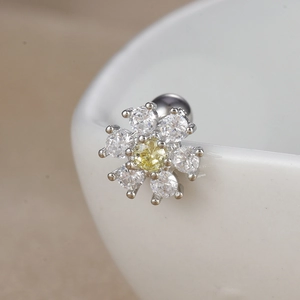 Vue rapprochée d'un piercing fleur argenté avec zircon jaune sur bord en céramique