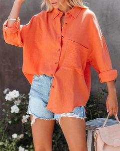Detail of orange cotton linen shirt showing textured fabric, V-neck, and button closure