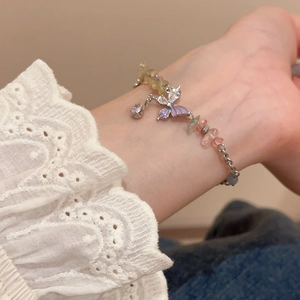 Detail of beaded bracelet with colorful natural stones and purple enamel butterfly charm