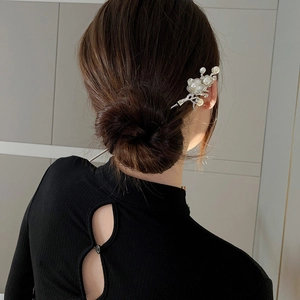 Close-up of lily of the valley hair pin with white petals and pearls on hair