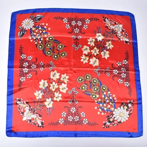 Close-up of floral print square scarf with red base and blue borders in satin finish