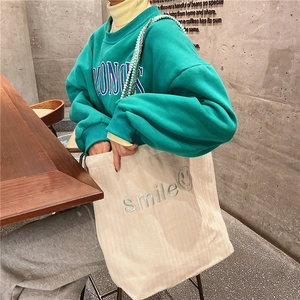 Detail of corduroy tote bag with smile embroidery and woven pearl chain strap