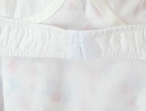 Detail shot of white fabric with colorful polka dots showing back hook-and-eye closure