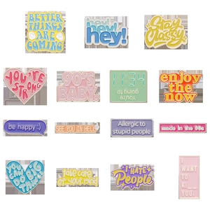 Macro display of colorful enamel lapel pins with inspirational slogans on white grid