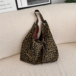 Detail of leopard print canvas tote bag featuring metal logo on white fleece surface