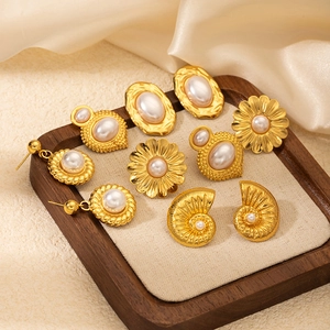 Detail view of vintage pearl flower and shell earrings on a soft cream background
