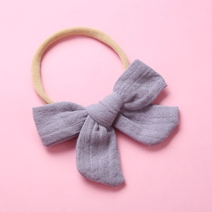 Detail of baby headband with a purple cotton muslin bow and soft beige nylon band