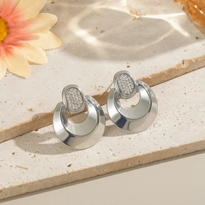 Close-up of geometric stainless steel earrings with sparkling diamonds on a stone base
