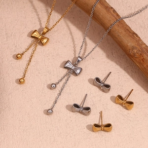 Detailed close-up of gold and silver bow necklaces and stud earrings on a wooden branch