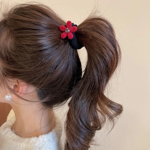 Détail d'un élastique à cheveux avec fleur floquée rouge et cristal central sur ruban noir