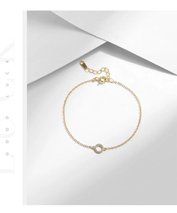Detail of gold chain bracelet with round micro-paved cubic zirconia pendant on white stand