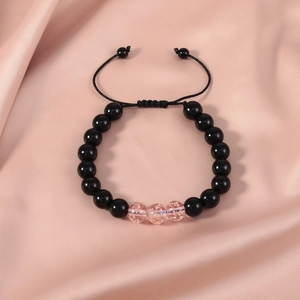 Detail of adjustable beaded bracelet with pink foil beads on soft pink silk background