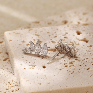Detailed view of S925 silver earrings with irregular zircon stones on a beige stone