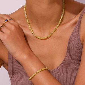 Detail of light yellow beaded necklace and bracelet set with golden spacer beads on model