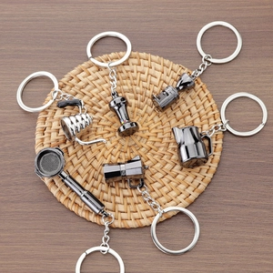 6-piece coffee tool keychain set featuring mini moka pot and espresso tamper on wooden desk