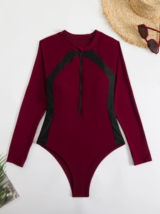 Détail de maillot de bain manches longues zippé avec lunettes rouges et chapeau de paille