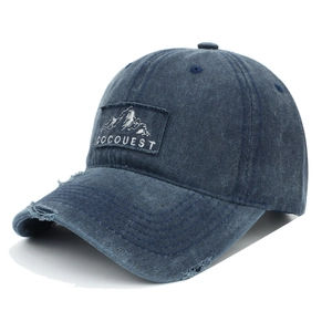 Detailed view of dark blue washed denim baseball cap with mountain patch and distressed holes