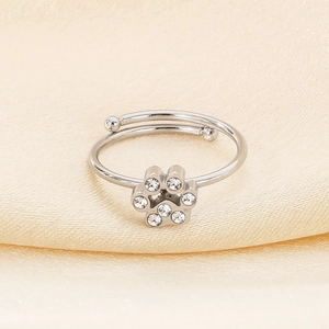Detail of adjustable silver cat paw ring with sparkling cubic zirconia on satin fabric
