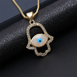 Macro shot of gold Hamsa Hand necklace with shimmering cubic zirconia and evil eye detail