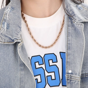 Close-up of a gold twist rope chain necklace worn by a model in casual denim jacket