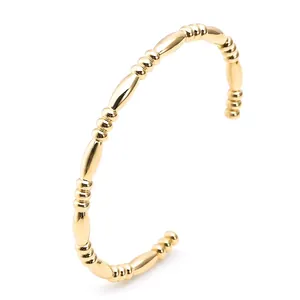 Golden C-shaped stainless steel bangle featuring vintage beaded and bamboo node design